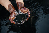 Fototapeta Łazienka - Hands are soaked in crude oil against the background of spilled petroleum products. The crisis of the oil industry. Economic downturn. Black gold. Copy space
