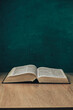 Open holy bible on a  wooden table. Beautiful green wall background.