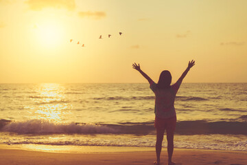 Wall Mural - Copy space of woman raise hand up on sunset sky at beach and island background.