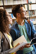 © NDABCREATIVITY - Group of happy students reading books and preparing to exam in library