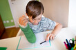 © epiximages - cool boy with green arm cast is sitting in his room and is writing something and is doing housework