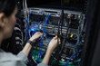 © Seventyfour - Close up of female network technician connecting cables in server cabinet while setting up supercomputer at data center, copy space