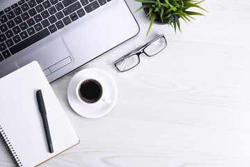 Top view of office work space, wooden desk table with laptop notebook,keyboard ,pen,eyeglasses,phone,notebook and cup of coffee.With copy space, flat lay.Mock up.