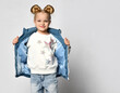 Studio shot of little blond girl unzip warm outwear blue sleeveless vest standing isolated over white background. Children trendy outfit and fashion advertisement. Design for shop, online store
