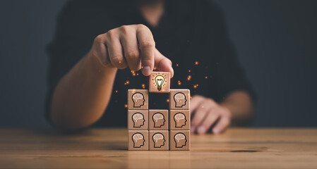 brainstorming creative idea and innovation. Hand putting over wooden cube block with light bulb icon on many people together having an idea symbolized by icons on cubes.