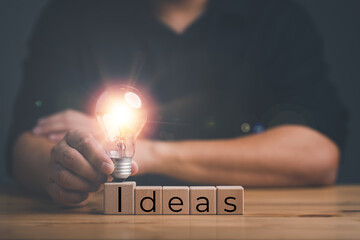 Poster - male Hand touching illuminated light bulb, new idea, innovation and inspiration concept, creativity with bulbs that shine glitter.