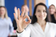 © H_Ko - Business woman showing ok gesture on background of colleagues closeup