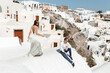 © Oleksandr - The couple is sitting on the roof in Santorini, hugging and laughing
