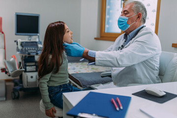 Wall Mural - Male doctor in white coat examining his little patient in clinic office