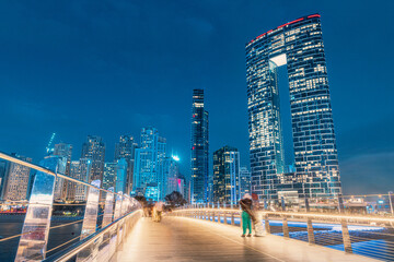Wall Mural - Panoramic view of footbridge with tourists leading to numerous skyscrapers with hotels and residential buildings on the Persian Gulf coast in Dubai during evening time