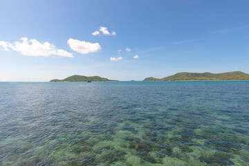 The sea water with many rocks under sea and the white clouds on the bright blue sky in the sunny day.