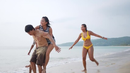 Wall Mural - 4K Group of Happy Asian man and woman friends running and playing together on tropical beach in sunny day. Male and female friendship enjoy and having fun outdoor lifestyle activity on summer vacation