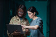 © Seventyfour - Waist up portrait of two women wearing military uniform using laptop while standing in server room, copy space