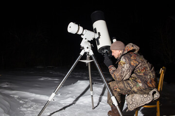 Wall Mural - a european man looks at the sky through a telescope. dark background.