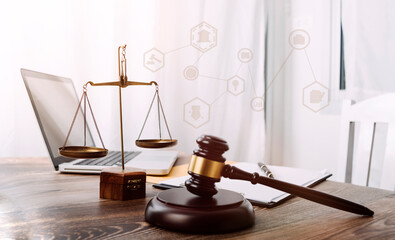 Justice and law concept.Male judge in a courtroom with the gavel, working with, computer and docking keyboard, eyeglasses, on table in morning light