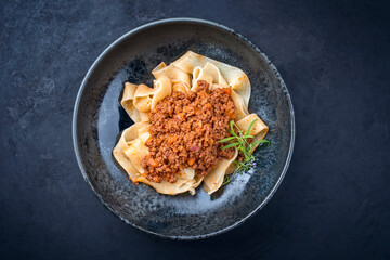 Wall Mural - Modern style traditional Italian ragu alla bolognese sauce with papedelle pasta noodles and parmesan cheese served as top view in a ceramic design bowl with copy space