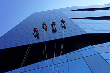 Window cleaners abseiling down the exterior of an office building in Rome, Italy.