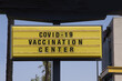 © Ole - Billboard saying Covid-19 Vaccination Center. With palm trees and blue sky background. Coronavirus pandemic vaccine concept.