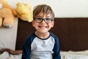 portrait of happy caucasian boy with eyeglasses sitting at home in room in day real people small mal