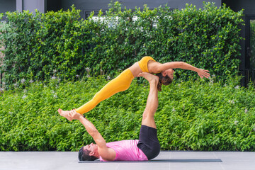 Wall Mural - athletic couple practicing acro yoga or yoga partner together in fitness park