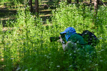 A photographer in a protective suit is looking for insects in the grass to work on