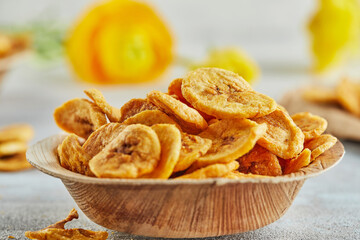 Poster - Banana chips healthy food, dry fruits and healthy vegetable chips, healthy vegan snack on background of yellow flowers