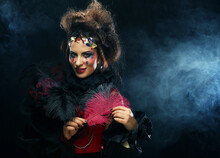 Beautiful Young Woman With Bright Makeup And Hairstyle Holding Red Ostrich Feather, Party And Carnival Theme.