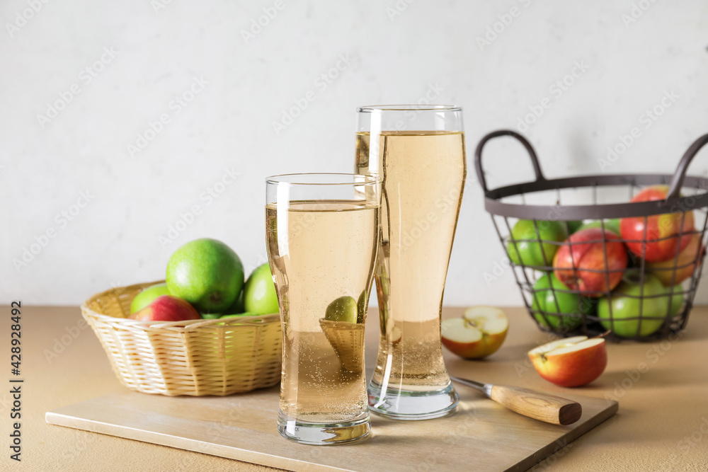 Glasses with apple cider and baskets on table