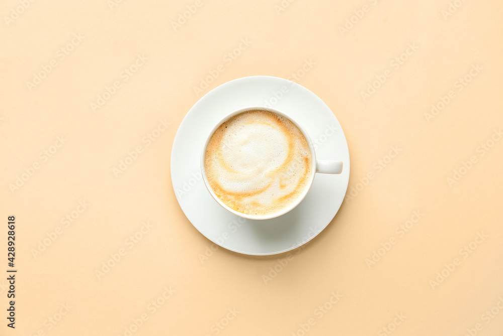 Cup of hot cappuccino coffee on color background