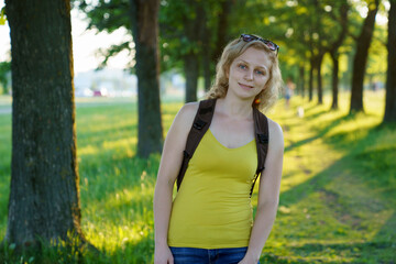 Young beautiful woman relaxing, feeling alive, breathing fresh air, having freedom in work or relationships, calm and dreaming with her eyes closed, in a green park