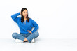 © luismolinero - Young mixed race woman sitting on the floor isolated on white background in back position and thinking
