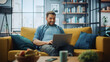 © Gorodenkoff - Handsome Caucasian Man Working on Laptop Computer while Sitting on a Sofa Couch in Stylish Cozy Living Room. Freelancer Working From Home. Browsing Internet, Using Social Networks, Having Fun.