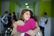 © liderina - Two best friends in high school.  Two girls hug. Students standing in school hallway. Focus is on foreground.