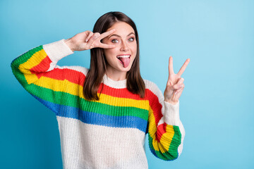 Sticker - Photo of nice impressed brunette lady show v-sign tongue out wear colorful sweater isolated on blue color background