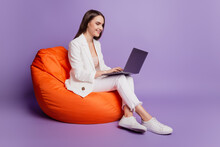 Close Up Profile Portrait Of Positive Lady Sit Beanbag Hold Computer Typing On Purple Wall