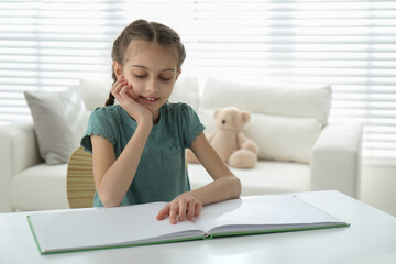 Sticker - Cute little girl reading book at desk in room. Space for text