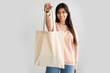 Cheerful woman standing with blank canvas tote bag