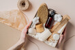 © photoguns - Beauty subscription Box preparation. Female hands holding gift box with natural skincare products, body brush, shampoo, soap, moisturizer.