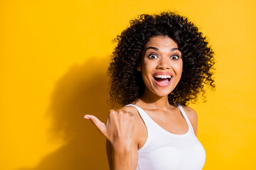 Poster - Photo of impressed dark skin woman dressed white tank-top pointing back thumb up empty space isolated yellow color background