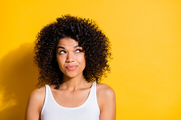 Poster - Portrait of pretty positive dark skin girl look interested empty space isolated on yellow color background