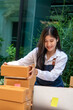 © PaeGAG - Young smiling beautiful owner asian woman freelance sme business online shopping working on laptop computer with parcel box on desk at home - SME business online and delivery concept
