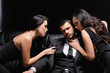 successful businessman near passionate women seducing him on leather couch on black.