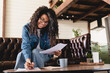 © InsideCreativeHouse - Busy young african businesswoman working with documents at home. African woman managing household finances at home,on calculator paying bills, account taxes or expenses