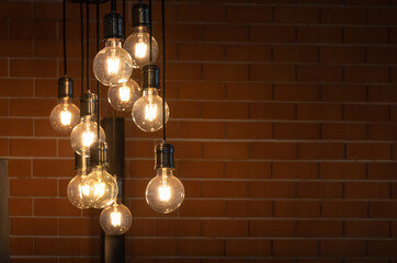 Wall Mural - vintage light bulbs are hanging from ceiling for decoration in living room with red brick background.