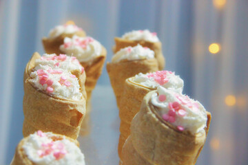 Wall Mural - Closeup of two lines of ice cream with pink sprinkles on it and orange bokeh in the background