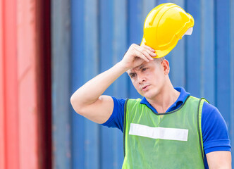 Wall Mural - Factory worker taking off yellow safety helmet at the cargo container