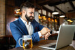 © NDABCREATIVITY - Handsome young business man, blogger or remote working with laptop in bar