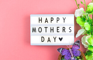  Happy Mother's Day text background, text message on a lightbox, pink workspace with spring flowers, holiday concept