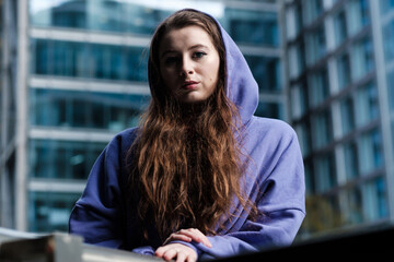 Wall Mural - Portrait of a young woman in a purple hooded sweat, financial environment.