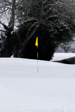 Yellow Golf Flag On Putting Green Covered In Snow